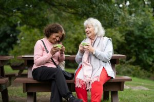 a couple of women sitting on top of a wooden bench